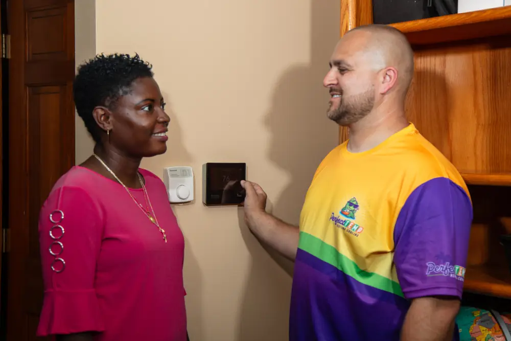 Ways to heat your house in Illinois winter - Perfect Temp technician showing digital thermostat money saving tips to customer.